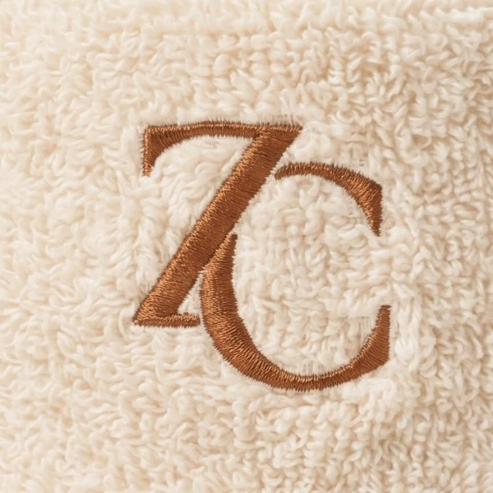 Close-up of the cognac ZC monogram on ivory terry